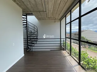 Ambiente interno com piso de madeira e grandes janelas de vidro.