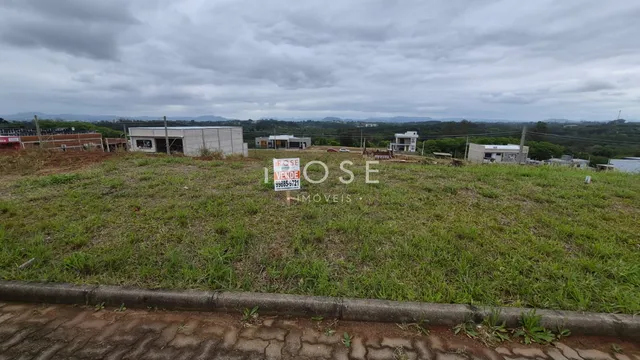 Vista de um terreno gramado com edificações ao fundo.