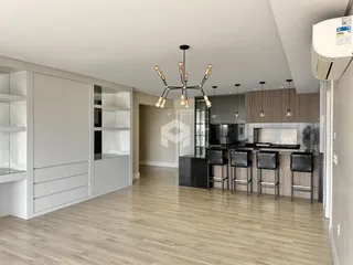 Vista de uma cozinha moderna com armários brancos e piso de madeira clara.