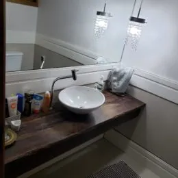 Bancada de pia branca com revestimento de madeira escura em um ambiente interno.