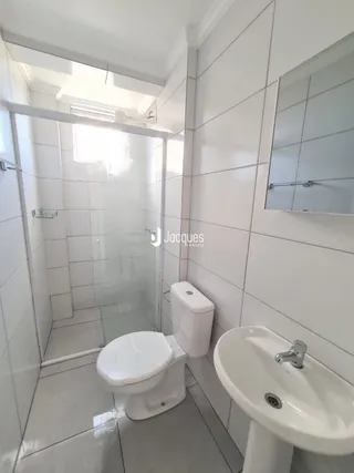 Foto de um banheiro com azulejos brancos e vaso sanitário branco.