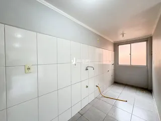 Vista interna de um corredor com paredes brancas e piso de cerâmica.