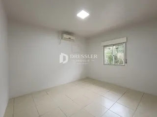 Ambiente interno de uma sala com piso de cerâmica e paredes brancas.