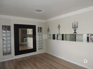 Foto de uma sala com piso de madeira clara e paredes brancas.