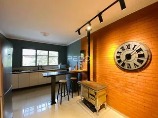 Interior de uma cozinha com parede de tijolos aparentes e piso claro.