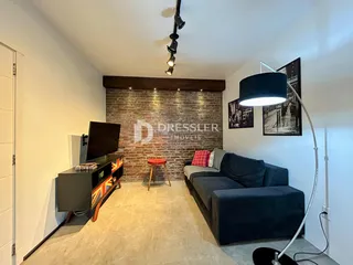 Sala de estar com parede de tijolos aparentes e sofá azul escura.