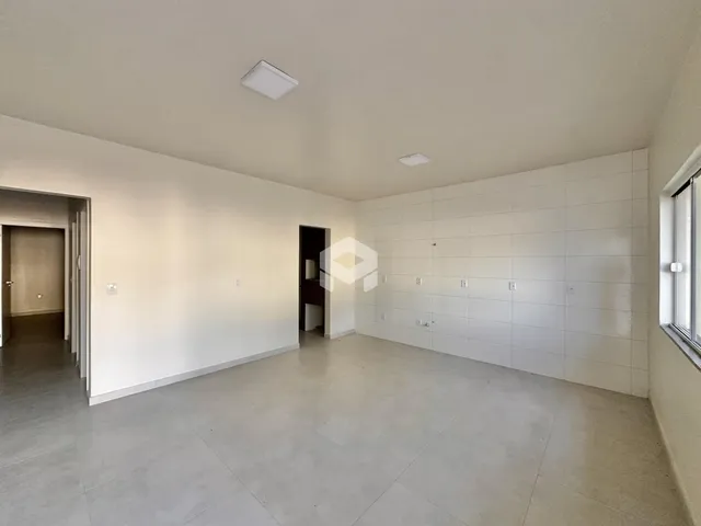 Um corredor amplo com paredes brancas e piso claro.