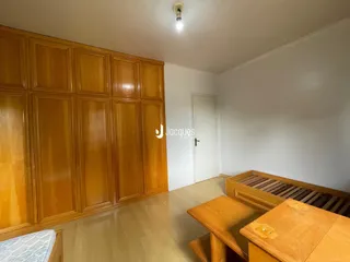 Quarto com painéis de madeira e piso claro.