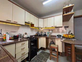 Cozinha com armários brancos e bancadas de granito em um imóvel no Brasil.