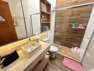 Banheiro com box de vidro e piso de madeira no imóvel.