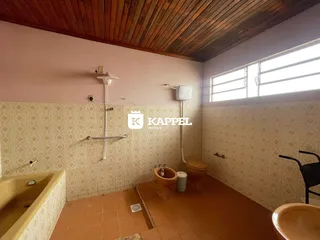 Banheiro com revestimento de azulejos e piso de cerâmica, apresentando uma banheira e vaso sanitário.