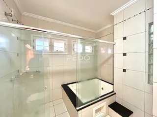 Banheiro com box de vidro e banheira em cerâmica.