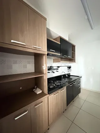 Cozinha moderna com armários de madeira e bancada preta.