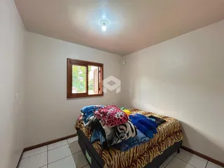 Quarto com cama e janela de madeira em uma residência.