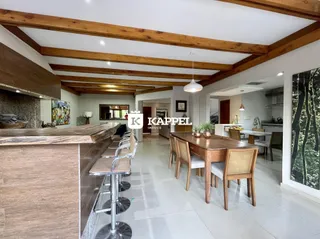 Foto de uma sala de jantar com mesa de madeira e ilha na cozinha.