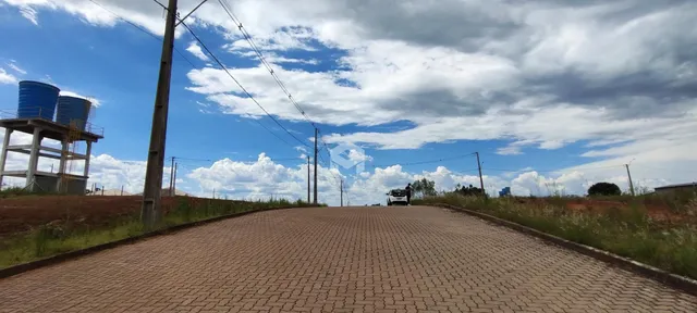 Uma estrada pavimentada leva a uma paisagem aberta sob um céu parcialmente nublado.