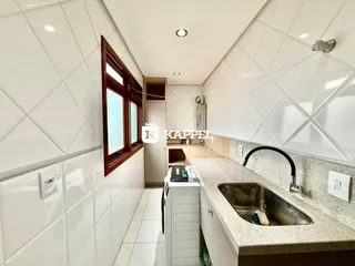 Foto interna de uma cozinha com bancada e janela em um imóvel.