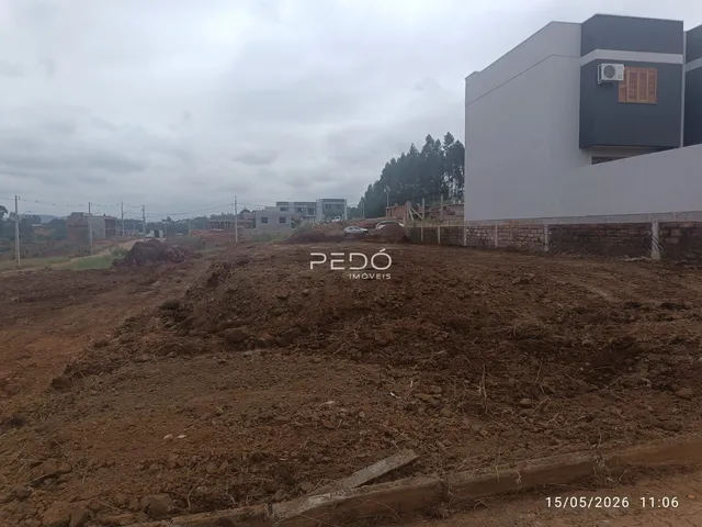 Foto de um terreno com terra exposta em frente a uma construção moderna.