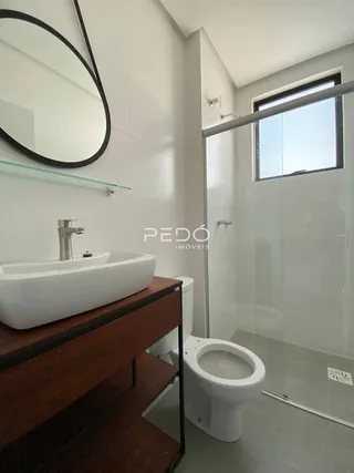 Banheiro moderno com box de vidro e louças brancas.