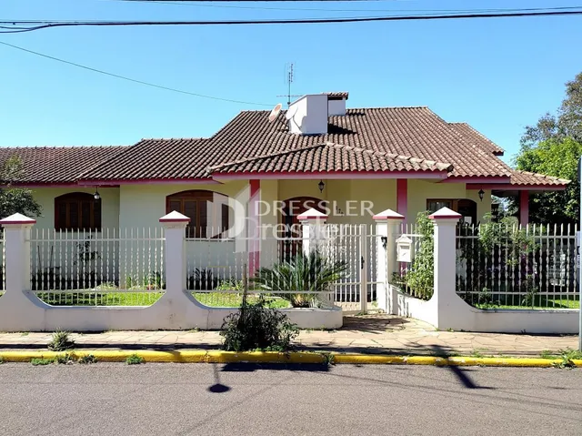 Fachada de uma casa residencial em Lajeado, Brasil com cerca branca e portão de ferro.