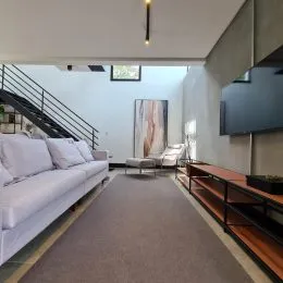 Foto da sala de estar mostrando um sofá e uma escadaria.