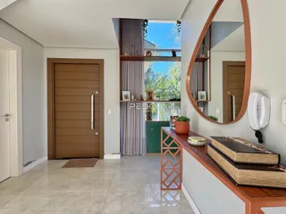 Hall de entrada com porta de madeira e piso claro em imóvel no Lajeado.