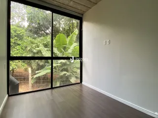 Vista interna de uma sala com grande janela de vidro em uma residência.