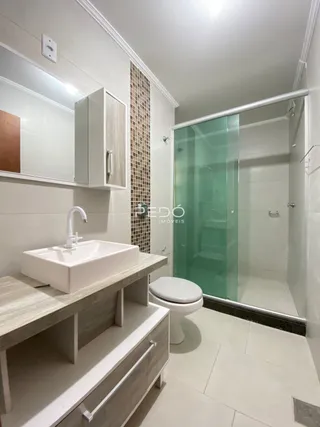 Foto de um banheiro com box de vidro e bancada branca.