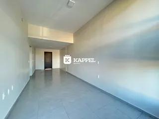 Corredor interno de uma residência com paredes brancas e piso de concreto.
