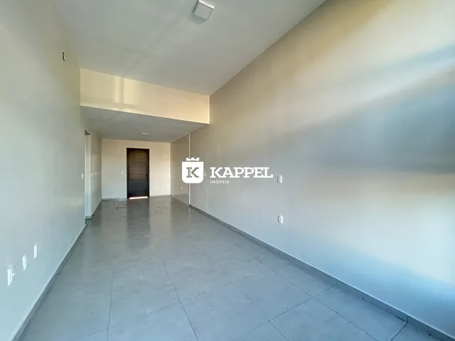 Corredor interno de uma residência com paredes brancas e piso de concreto.