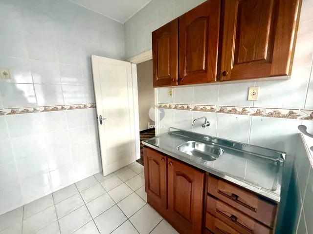 Interior de uma cozinha com armários de madeira e azulejos brancos.