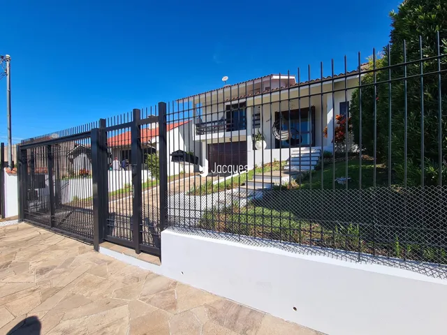 Fachada de uma residência com cerca de ferro e muro branco em Lajeado.