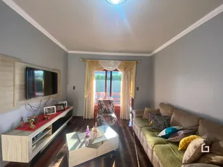 Sala de estar com sofá e televisão em um imóvel.