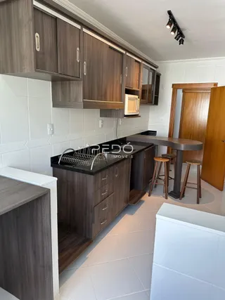 Vista interna de uma cozinha com armários de madeira e piso claro.