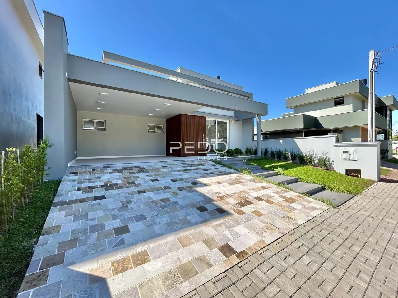 Fachada moderna de uma residência com área externa pavimentada.
