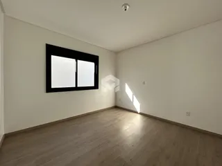 Uma sala de estar com piso de madeira clara e grande janela.