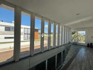 Vista de uma sala com grandes janelas que dão para a rua.