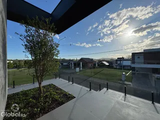Vista de uma área externa com gramado e árvores de uma residência.