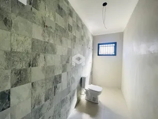 Corredor interno com revestimento de azulejos cinzas e piso claro.
