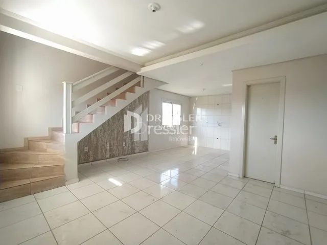 Vista interna de um corredor com escadaria e piso de cerâmica clara.