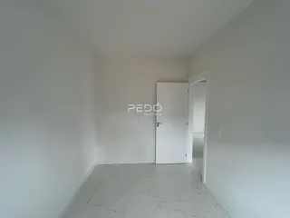 Hall de entrada com piso de porcelanato claro e paredes brancas.