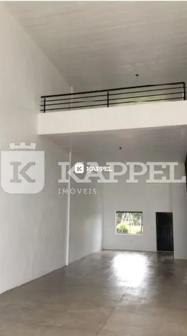 Hall de entrada com paredes brancas e piso de concreto.