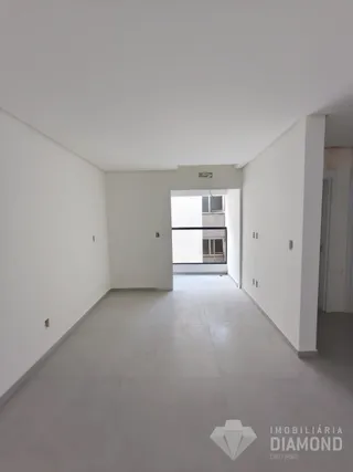 Hall de entrada com paredes brancas e piso cinza em um imóvel.
