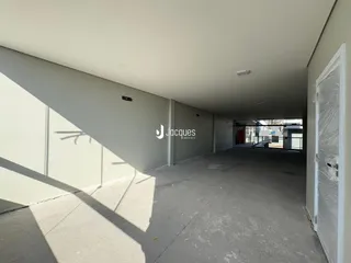 Vista de um corredor interno com paredes brancas e piso de concreto.