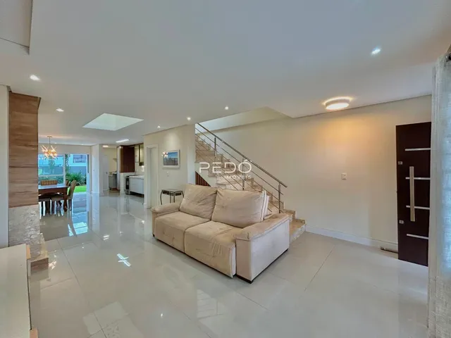 Sala de estar com piso de cerâmica e sofá claro em um imóvel em Lajeado.