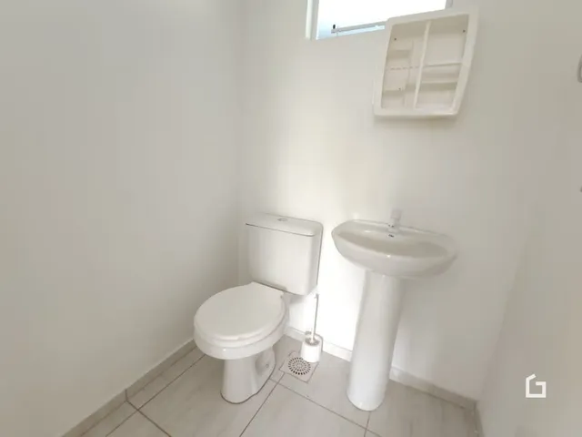 A foto mostra um banheiro com vaso sanitário e pia brancos.