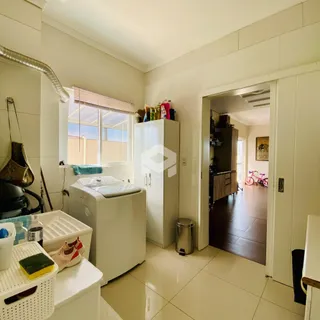Interior de uma área de serviço com máquina de lavar e armário branco.
