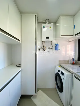 Interior de uma cozinha com armários brancos e máquina de lavar roupa.