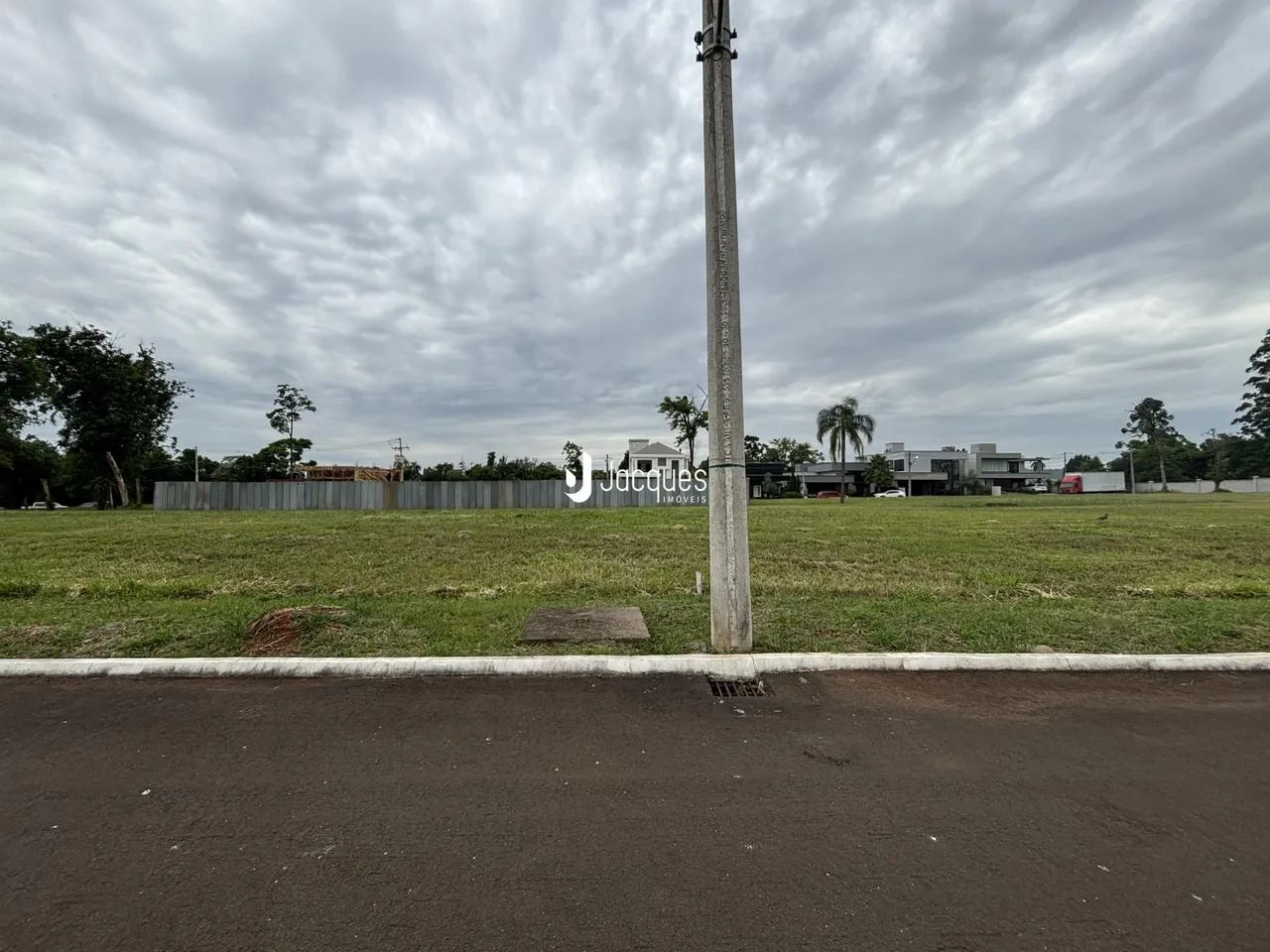 Vista externa de uma propriedade com gramado e poste no meio.