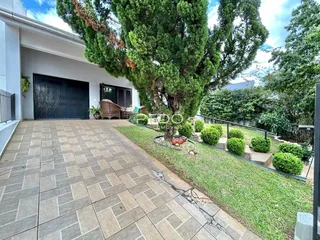 Vista da fachada de uma residência com área pavimentada e jardim.